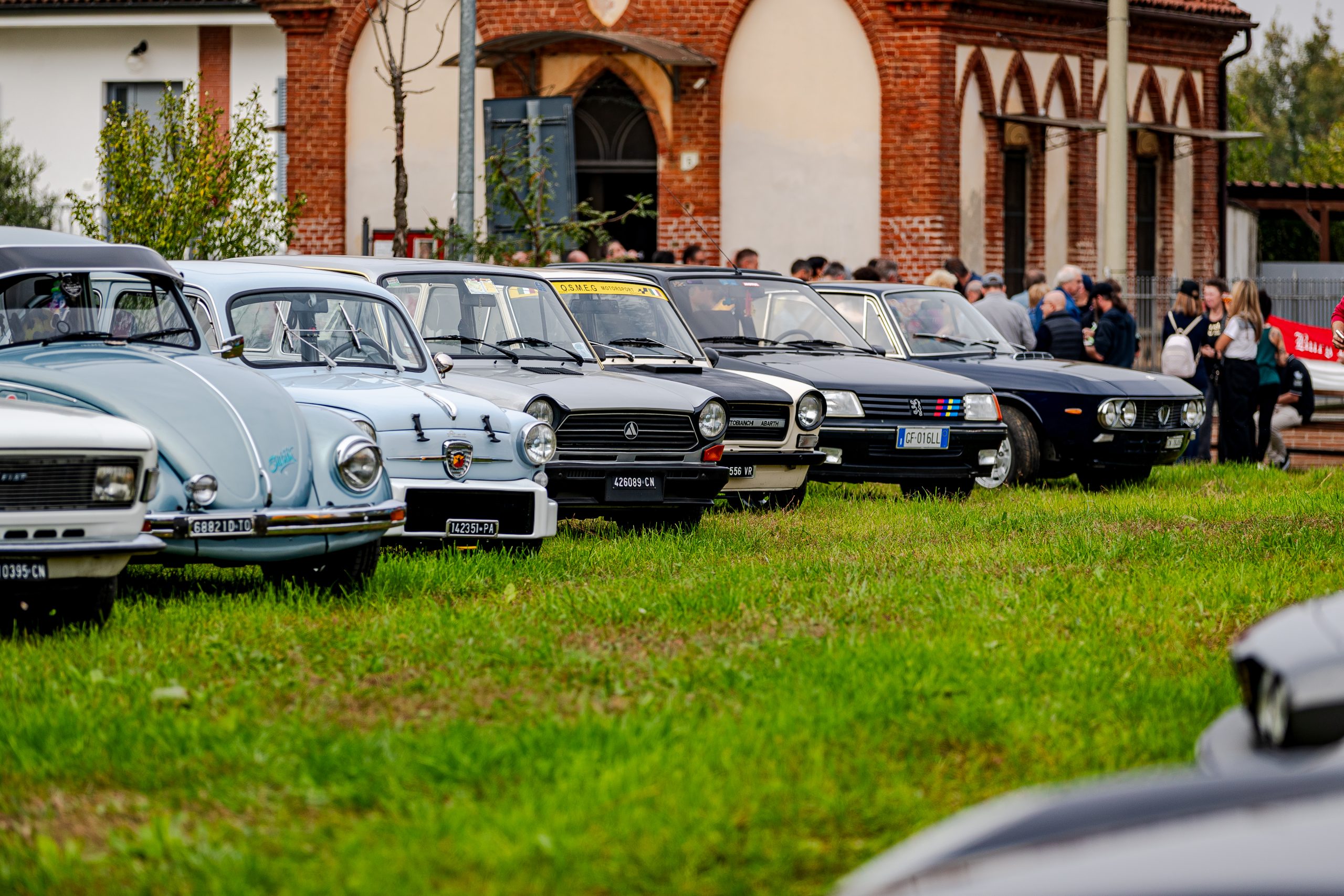 Auto d'epoca in fila sul prato davanti alla chiesa durante Storico Sanfrè 2025 a Sanfrè
